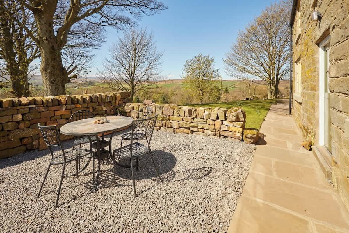 An outdoor seating area with a stone wall, a round table, and chairs.