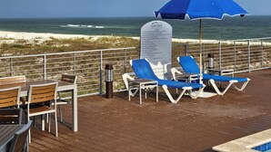 A deck with lounge chairs and a table, overlooking the beach and ocean. - Salty and Sweet at Perdido Key  SLEEPS 8! Two pools and a state-of-the-art gym (Pensacola)