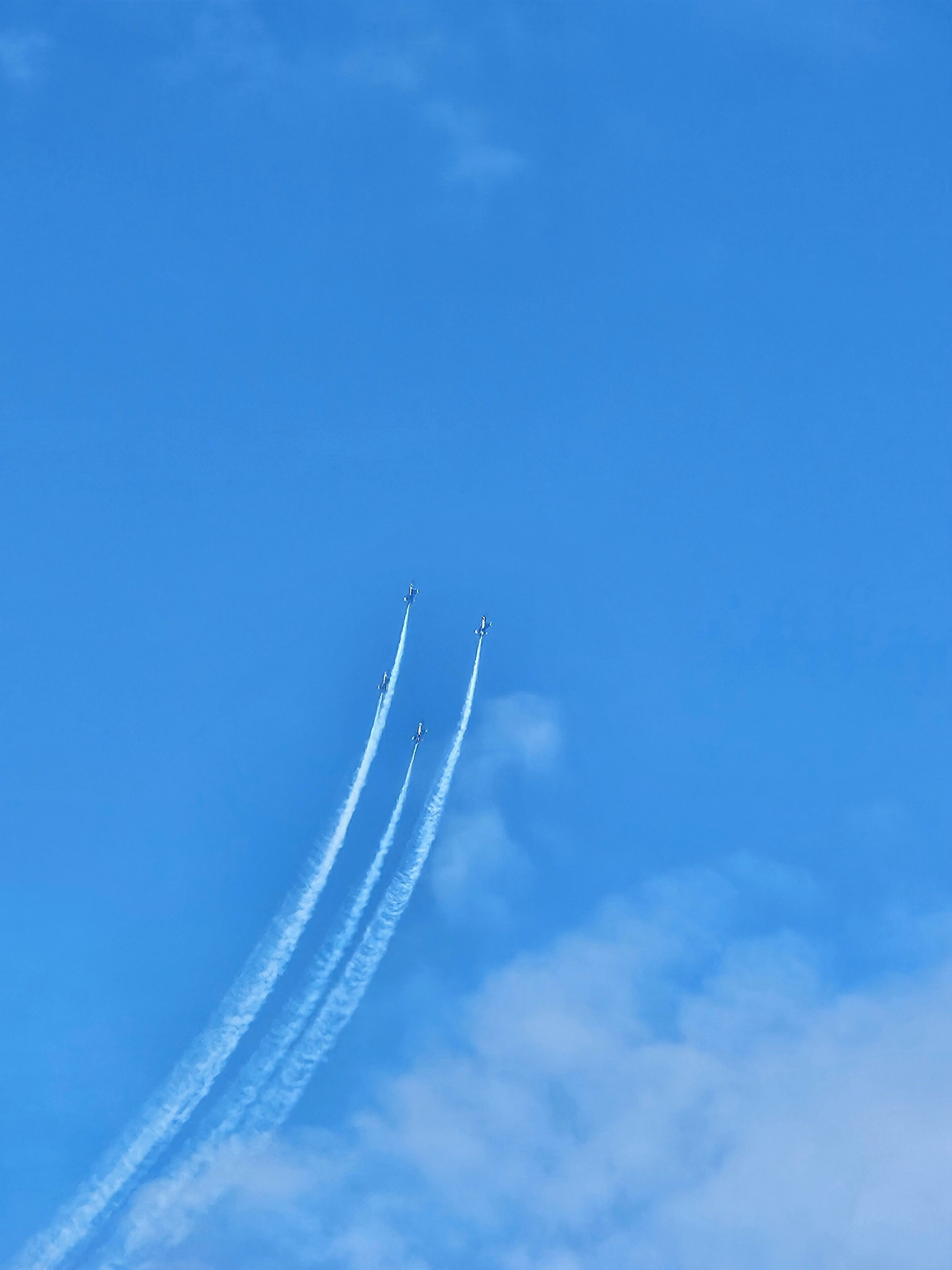 Tres aviones volando en formación dejando estelas sobre un cielo azul despejado.