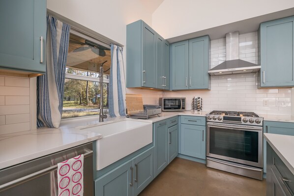 A modern kitchen with light blue cabinets, a stainless steel stove, and a microwave. - 2 ACRE Modern Resort w/ HUGE Pool (St. Augustine)