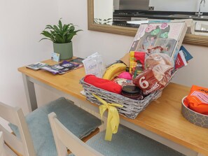 A desk with a wicker basket containing snacks, a plant, and some magazines.