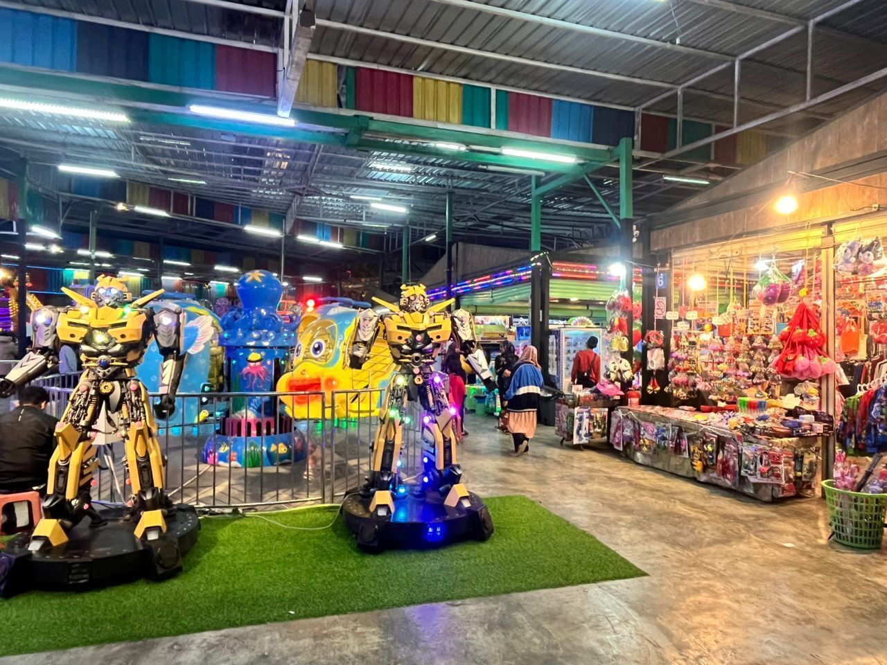 Un amplio espacio de entretenimiento cubierto con diversas atracciones y una tienda de recuerdos.