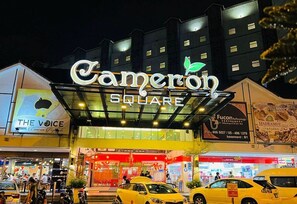 L’entrée d’un hôtel, avec une enseigne indiquant « Cameron Square » et « The Voice » sur le côté gauche.