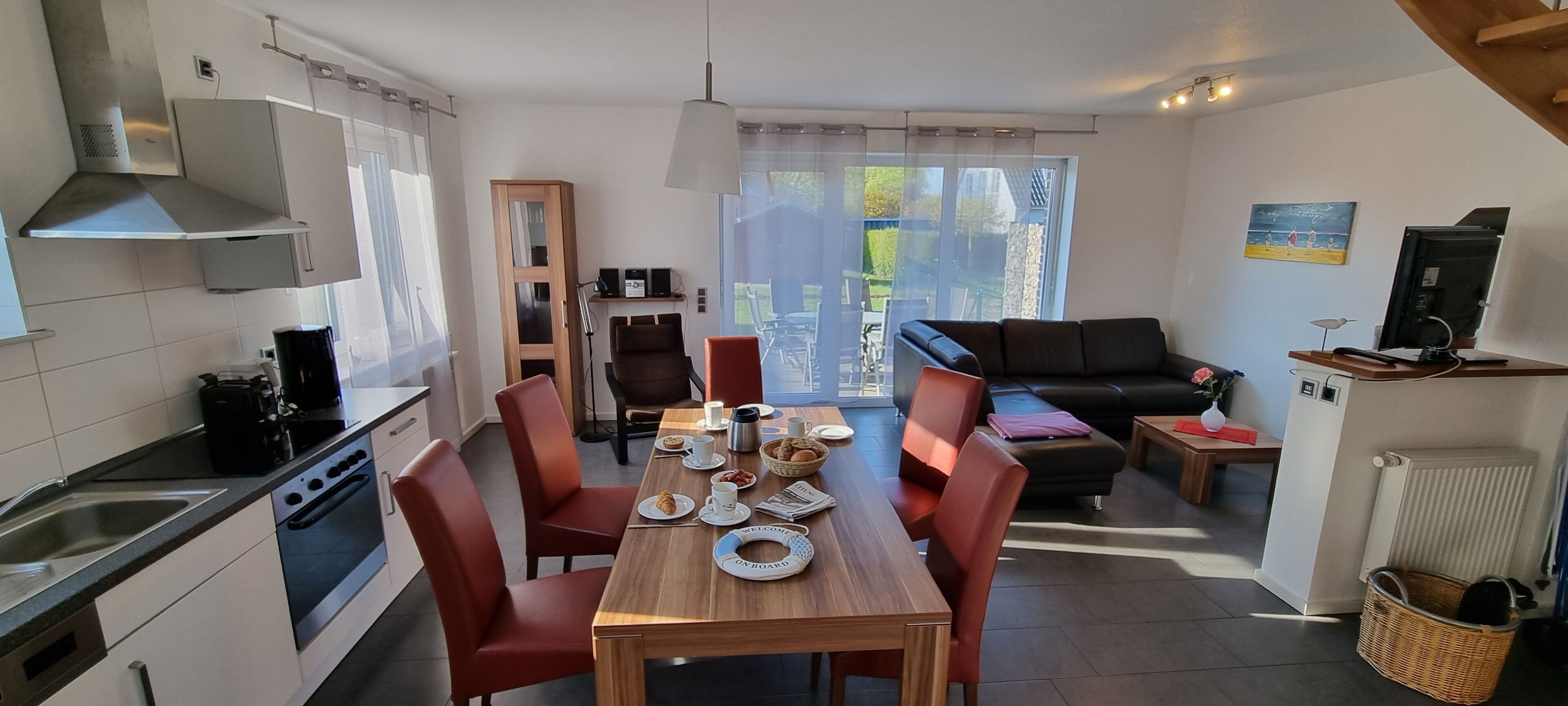 Cocina moderna con comedor, sofá y televisor.