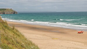 A beach with a clear view of the ocean, a grassy area, and a lifeguard station.