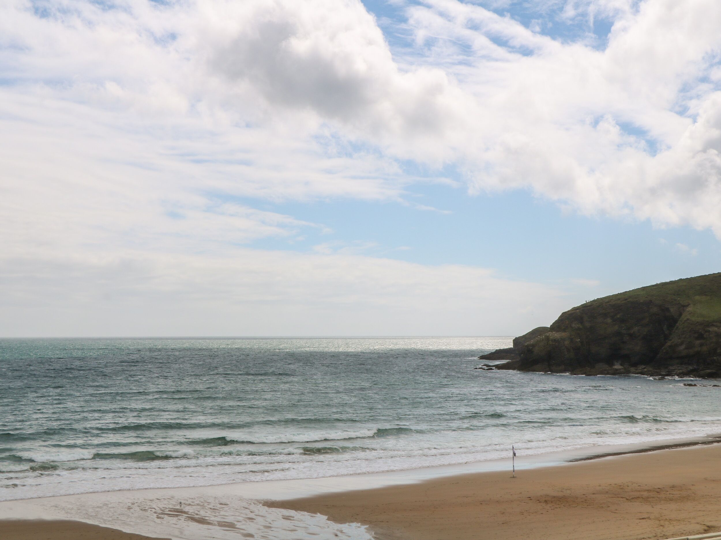 A beach with a sandy shore and a rocky cliff.