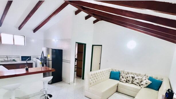 A modern living room with a sofa, a wooden table, and a kitchen area with a refrigerator and a microwave. - CENTRAL APARTMENT IN POPAYAN (Popayán)
