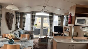 A compact living space with a dining area, sofa, television, and kitchenette. - Prestige pet Friendly Caravan on Butlins, Skegness (Skegness)