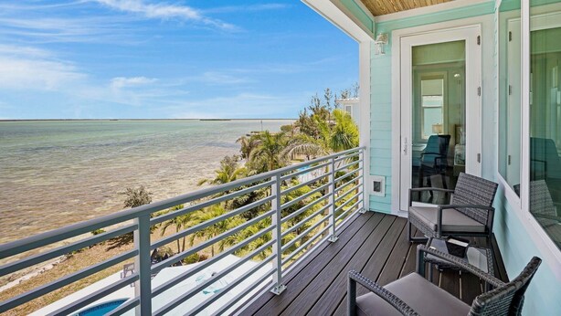 A balcony with a view of the ocean, a pool, and outdoor furniture. - **BLUE HORIZON @ SUGARLOAF SHORES** Home + Last Key White Glove Service... (Sugarloaf Key)