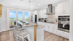 A modern kitchen with white cabinets, a stainless steel range hood, and a large island with bar stools. - **BLUE HORIZON @ SUGARLOAF SHORES** Home + Last Key White Glove Service... (Sugarloaf Key)