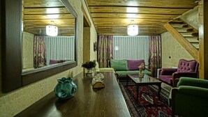 Una sala de estar acogedora con techo de madera, un espejo grande, un sofá, una mesa de centro y una escalera.