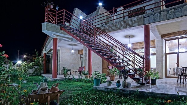 Un edificio de varios niveles con una escalera roja destacada, zona de estar al aire libre y plantas en macetas.