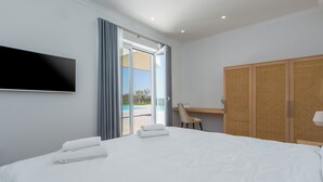 A hotel room with a bed, a TV mounted on the wall, a desk, and a wardrobe. - Villa Villa Borgonja (Istria - Brtonigla) (Brtonigla)