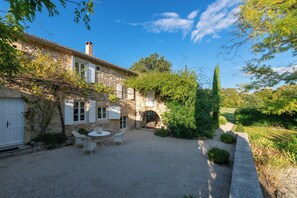 Un bâtiment en pierre doté d’une terrasse en gravier, de sièges extérieurs et d’un jardin.