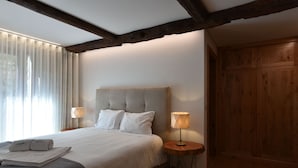Ein Schlafzimmer mit einem großen Bett, zwei Nachttischlampen, einem Holzschrank und einem Fenster mit Vorhängen.