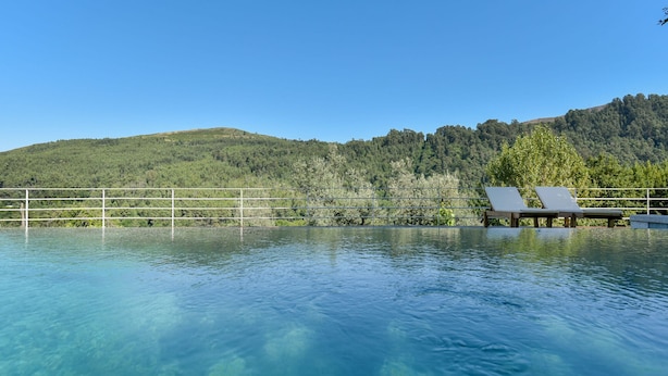 Ein klares Schwimmbecken mit zwei Liegestühlen und einem Metallgeländer.