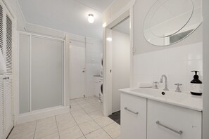 Een moderne badkamer met een inloopdouche, toilet en een wastafel met spiegel erboven.