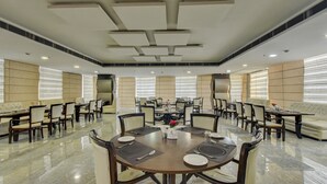 A spacious conference room with a high ceiling, multiple tables, and chairs arranged for meetings. - Treebo Elysee, Patel Nagar (Dehradun)