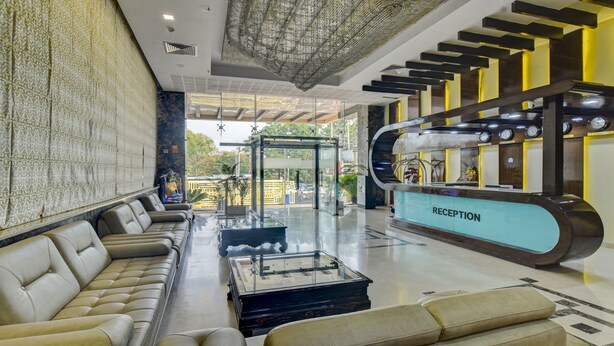 A modern reception area with a glass partition, leather seating, and a reception desk. - Treebo Elysee, Patel Nagar (Dehradun)
