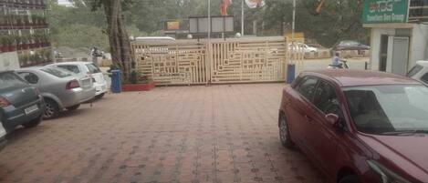A parking area with cars, a gated entrance, and a building with a sign for 'Travelers Den Group'.