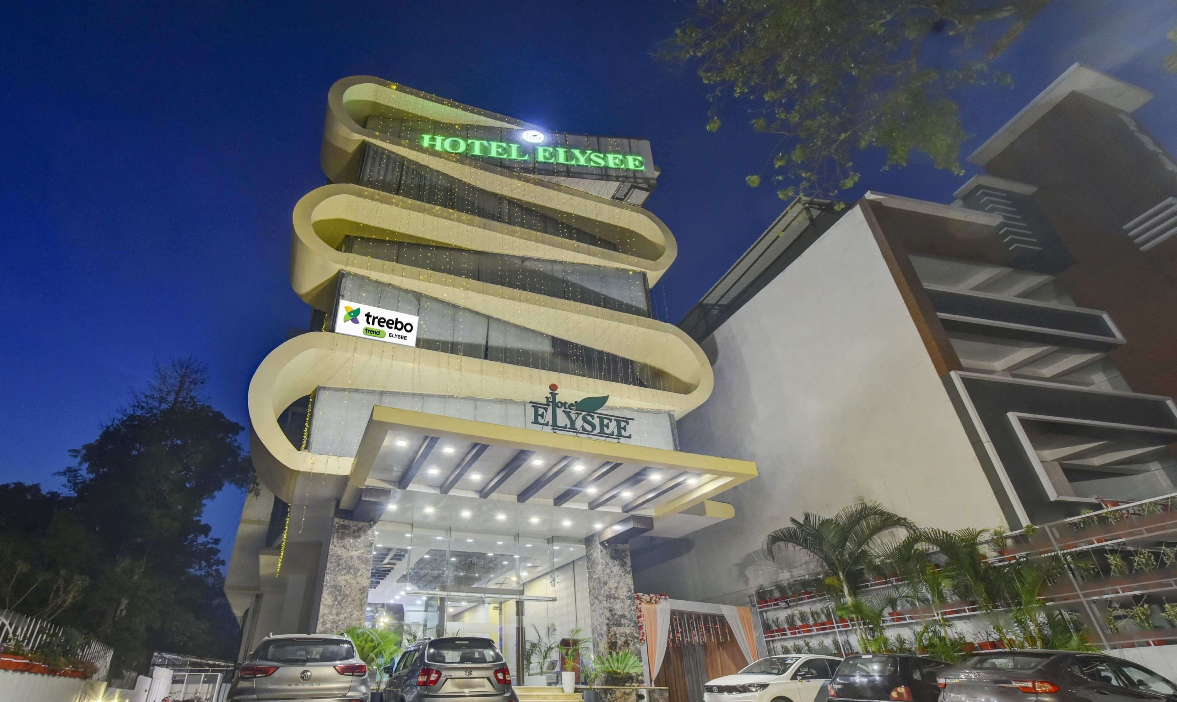 A modern hotel with a curved facade, signage for 'Hotel Elysee', and a 'treebo trend' logo.