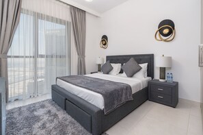 A modern bedroom with a large bed, a nightstand, a lamp, and a view of the city. - New! Luxurious Living Dubai Creek Balcony & View (Dubai)
