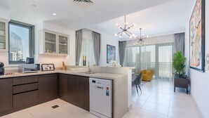 Una cocina moderna con lavavajillas, un comedor con una silla amarilla y un amplio ventanal con vistas a la ciudad.