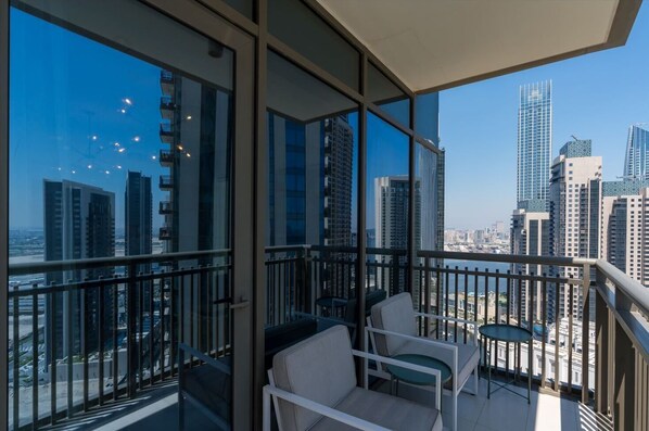 Enjoy unobstructed city views from the balcony with a sofa, table, and chairs.