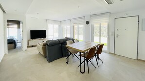 A modern living room with a sofa, a TV, and a dining table with chairs. - 3084 Res. MAUI II (Orihuela)
