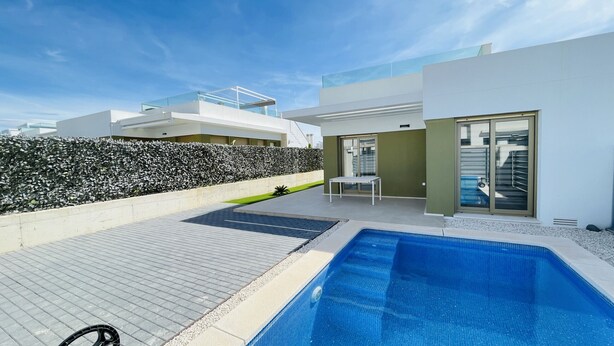 A modern outdoor swimming pool with a clear blue water surface, surrounded by a paved deck area. - 3084 Res. MAUI II (Orihuela)