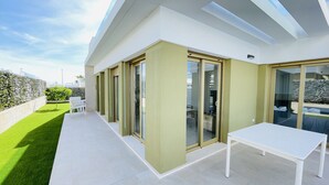 A modern house with a patio, sliding glass doors, and a white table. - 3084 Res. MAUI II (Orihuela)
