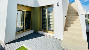 A modern white building with a glass door and a staircase leading to a higher level. - 3084 Res. MAUI II (Orihuela)
