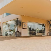 A hotel entrance with a large glass door, a potted plant, and a sign with a capital 'H'.