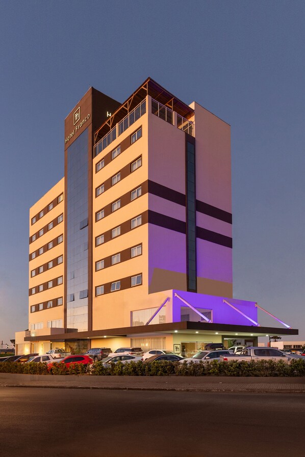 Un hotel de varios pisos con un diseño moderno, que destaca por una estructura vertical prominente y un techo plano.