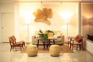 A modern living room with a sofa, two armchairs, a coffee table, and a large abstract wall art piece.