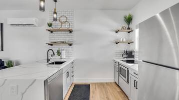 Una cocina moderna con armarios blancos, electrodomésticos de acero inoxidable y piso de madera.