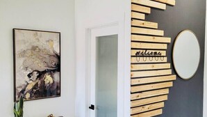Een modern interieur met een wanddecoratie van hout, een gekaderd abstract schilderij en een console tafel met een plant.