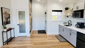Een moderne keuken met een houten vloer, witte kasten en een zwarte magnetron.