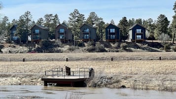 A series of cabins with a dock extending into a body of water, surrounded by a natural landscape.