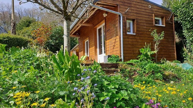 Une cabane en bois avec un jardin devant.