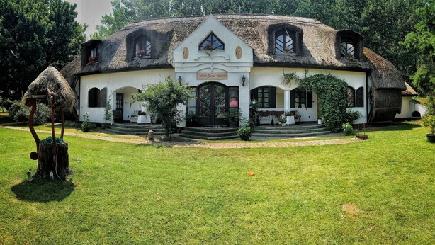 Una casa tradicional con techo de paja, múltiples ventanas y una entrada principal con escalones.