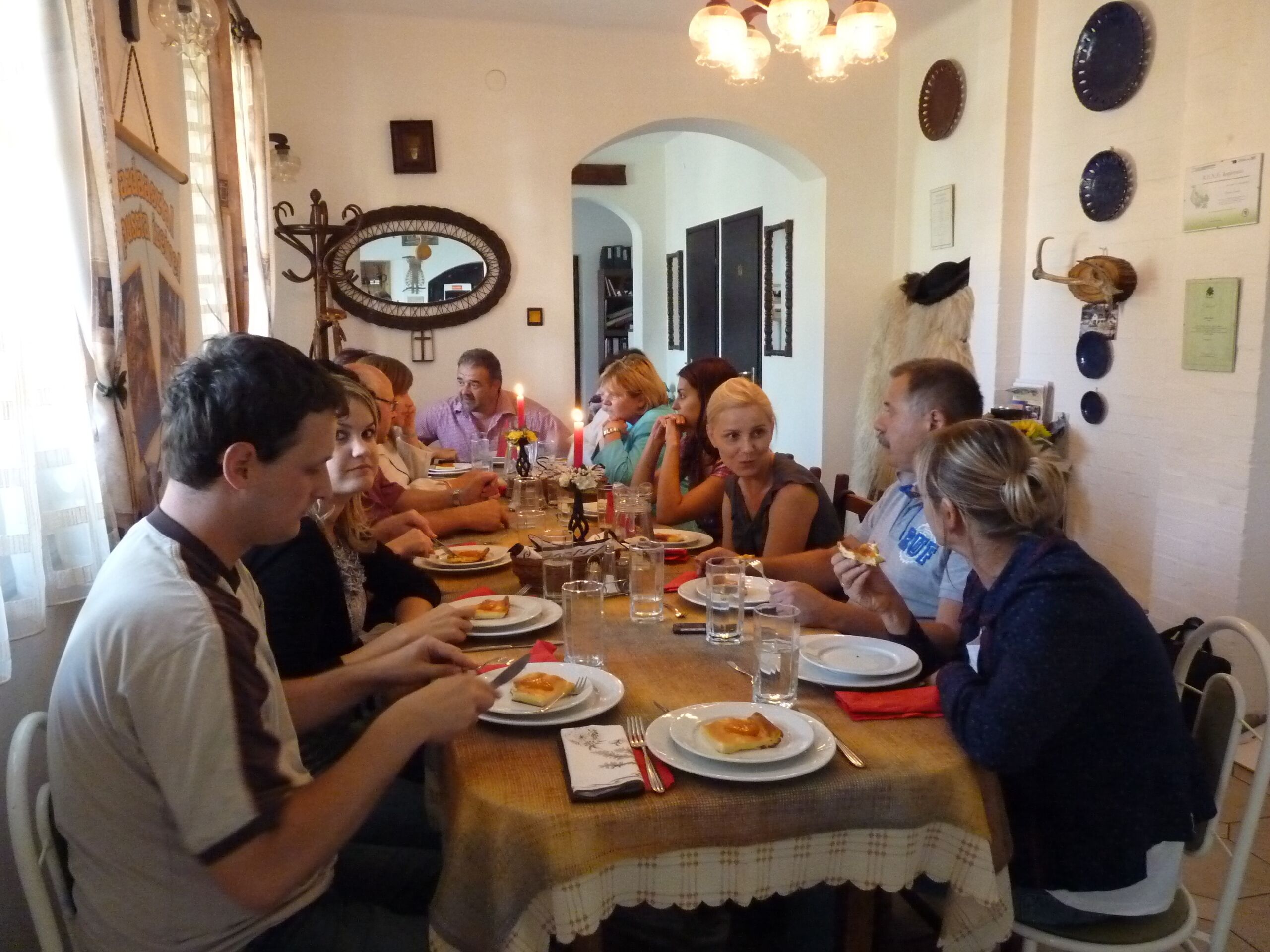 A dining room with a table set for a meal, surrounded by chairs.