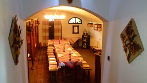 Un pasillo que conduce a un comedor con una larga mesa, un candelabro y un gran cráneo de toro en la pared.