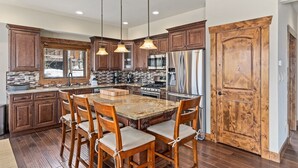 A spacious kitchen with wooden cabinets, a granite island, and stainless steel appliances. - Cherry Drive 4 Bedroom Home by RedAwning (Steamboat Springs)