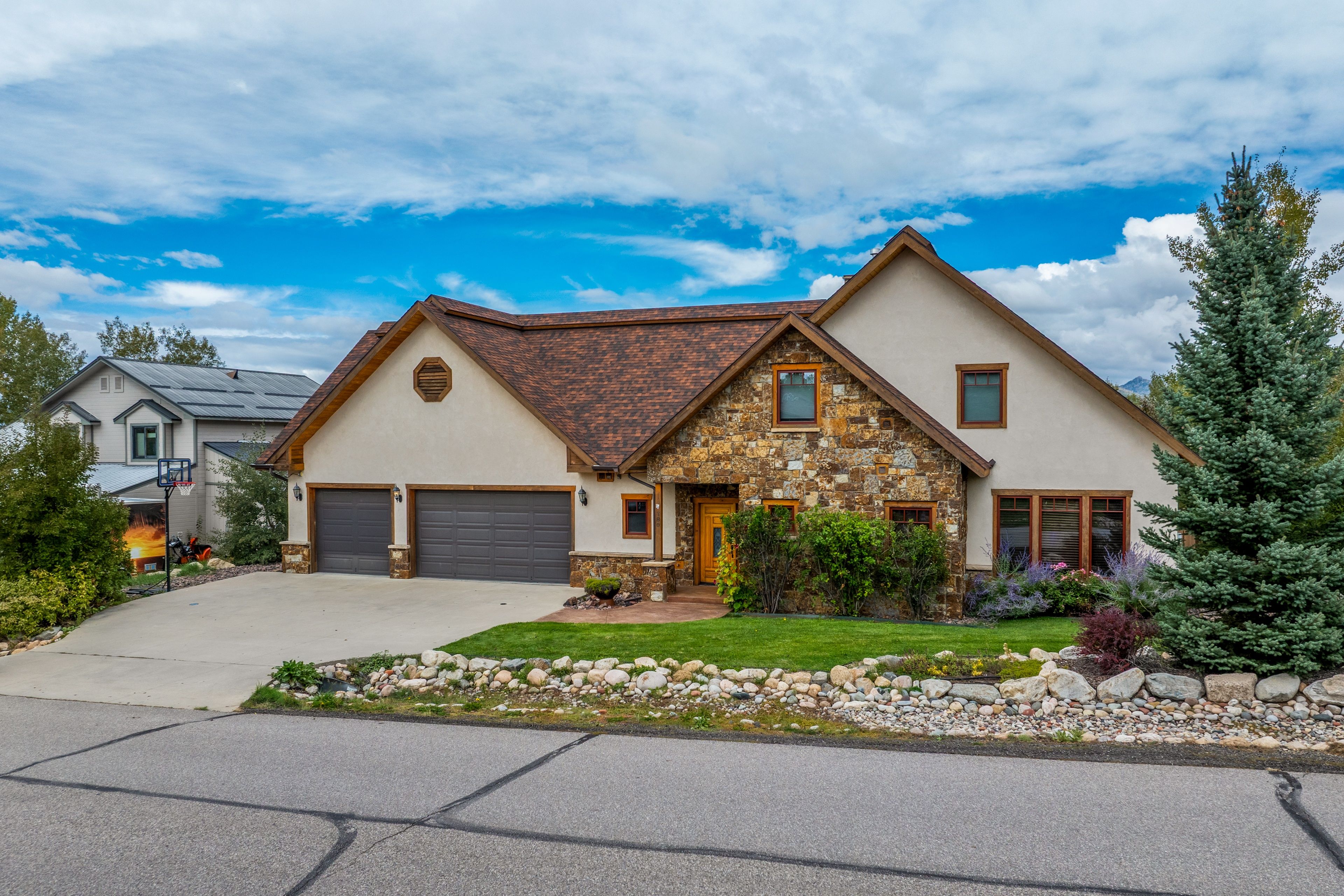 A two-story house with a stone facade, a garage, and a well-maintained lawn.