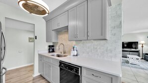 Una cucina moderna con mobili grigi, una lavastoviglie, una macchina da caffè e un lavello.