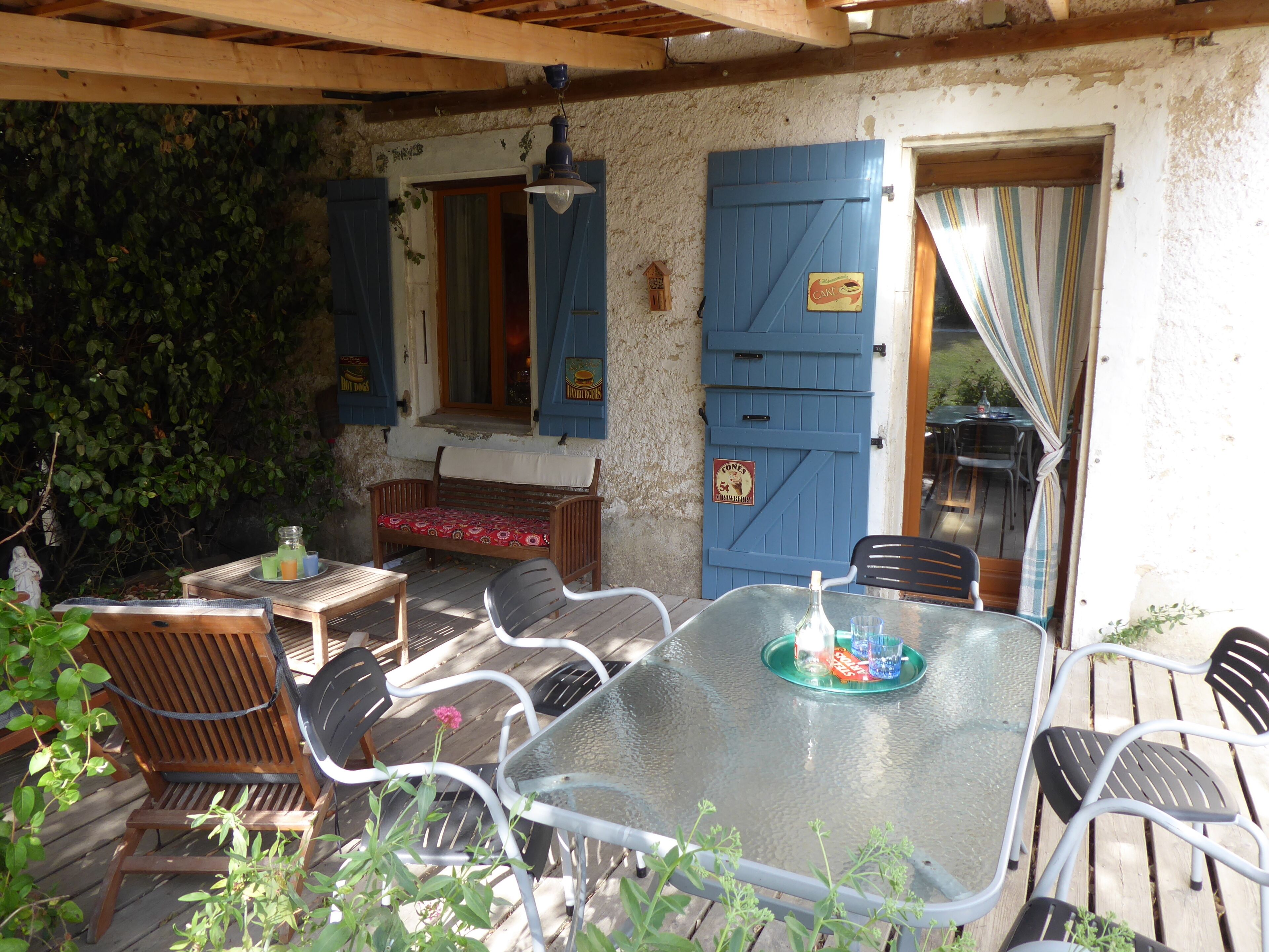 An outdoor patio with a table, chairs, a bench, and a blue door with a sign.