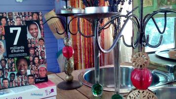 A wooden table with a stack of books, a decorative metal stand, and a vase with dried lavender.