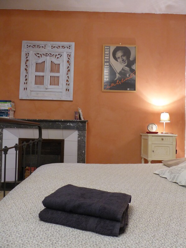 Un dormitorio con una cama, una mesita de noche con lámpara, un reloj de pared y un cartel.