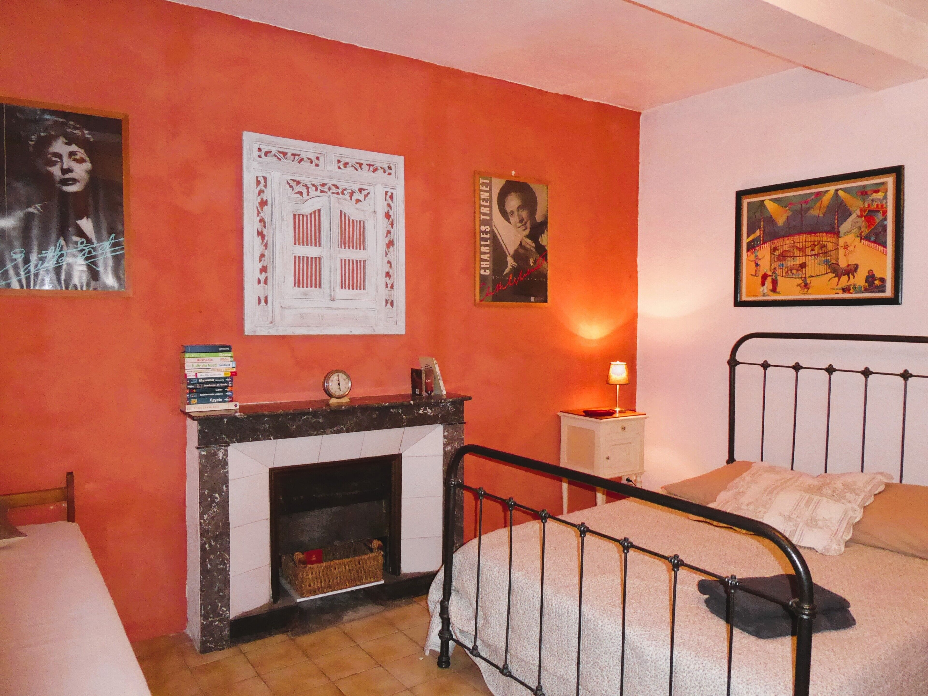 Ein Schlafzimmer mit Bett, Nachttisch, Kamin und Wandbildern.